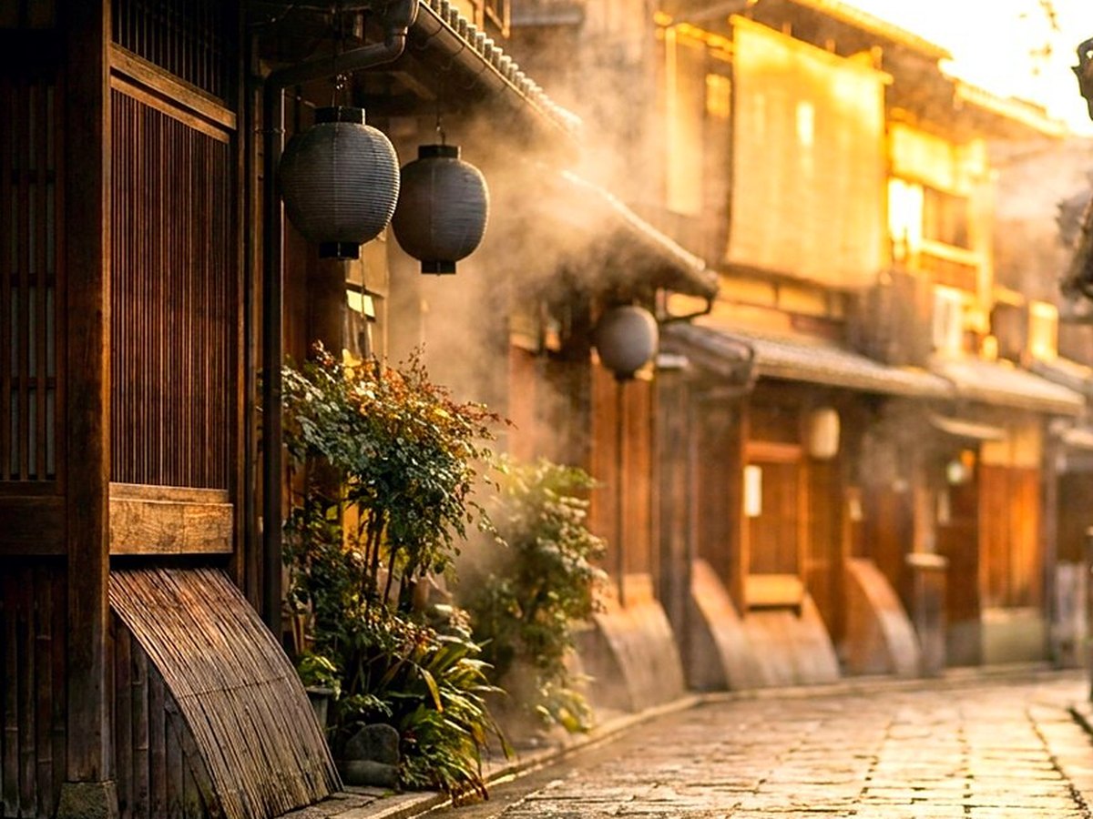 A stone bridge over a shallow canal between wooden houses in early morning light